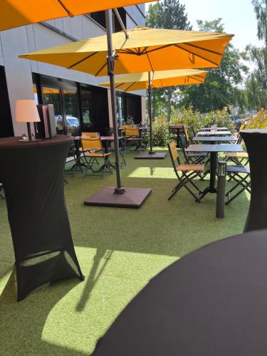 a patio with tables and chairs with umbrellas at Best Western Plus Le Conquerant Rouen Nord in Bois-Guillaume