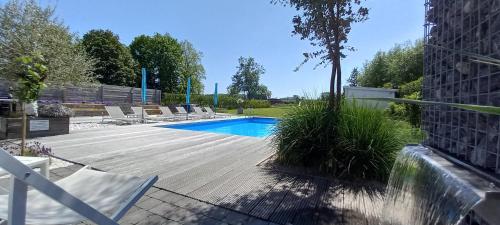 a swimming pool with lounge chairs next to a building at Vakantievilla - B&B Blue Garden Vlaamse Ardennen in Geraardsbergen