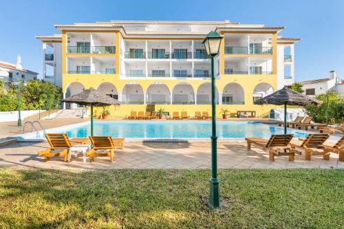 a hotel with a swimming pool with chairs and umbrellas at Apartamentos Turisticos Alagoa Praia in Altura