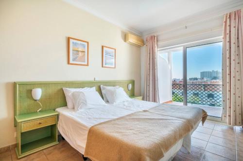 - une chambre avec un lit et une grande fenêtre dans l'établissement Apartamentos Turisticos Alagoa Praia, à Altura