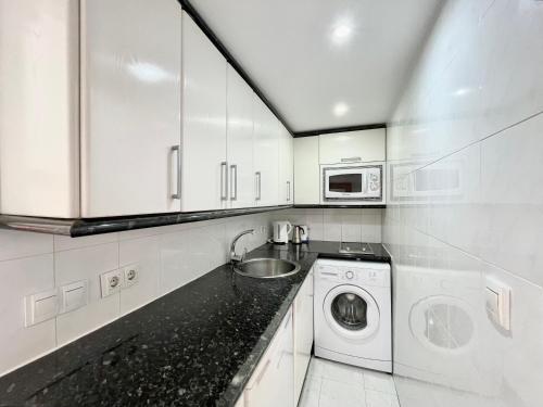 a white kitchen with a washing machine and a sink at Estudio en primera línea de playa in Fuengirola