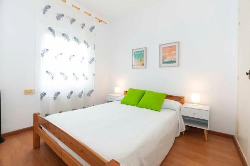 1 dormitorio con cama blanca y almohadas verdes en 1141 Mas Oliva, en Roses