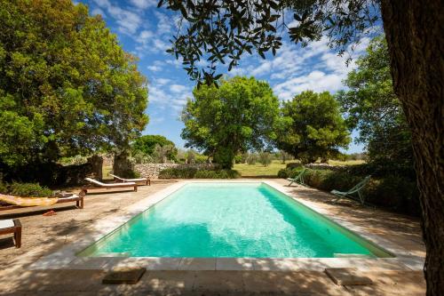 einen Pool in einem Garten mit Bänken und Bäumen in der Unterkunft Masseria Casino Mattia in Surano