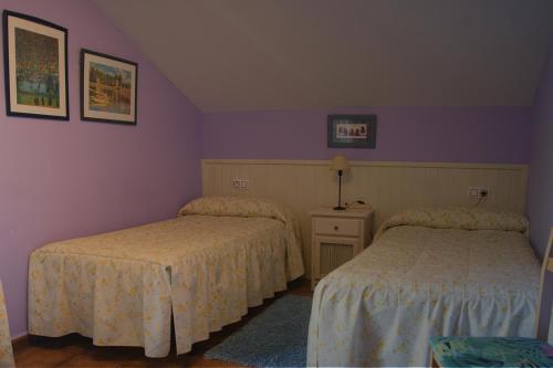 two beds in a room with purple walls at Casitas Del Huerto in La Alberca