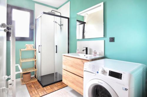 une salle de bain avec une machine à laver et un lavabo dans l'établissement Gîte Anna - Maison à proximité de la mer, à Saint-Jean-de-la-Rivière