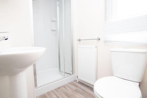 Baño blanco con aseo y lavamanos en Skegness Holidays en Skegness