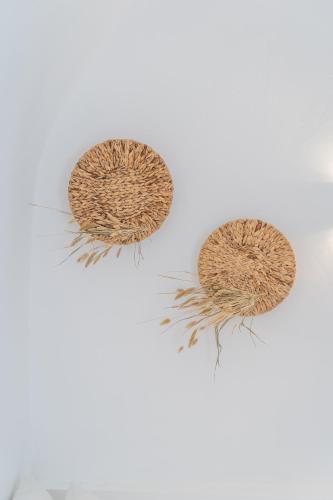 three straw hats on a white wall at Luxus VIP Suites in Oia