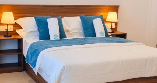 ein Schlafzimmer mit einem großen Bett mit blauen und weißen Kissen in der Unterkunft Vaagali Inn in Felidhoo 