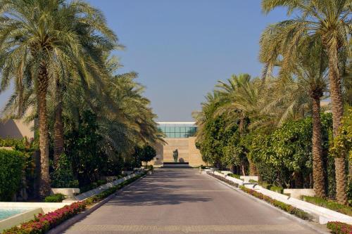 Meliá Desert Palm Member of Meliá Collection في دبي: طريق تصطف فيه أشجار النخيل ومبنى