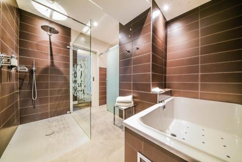 a bathroom with a tub and a glass shower at Le Clervaux Boutique Hotel & Spa in Clervaux