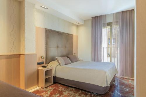 sypialnia z łóżkiem i oknem w obiekcie Hotel Gótico w Barcelonie