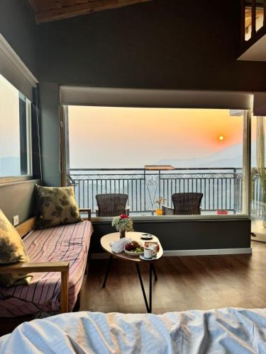 a bedroom with a large window with a view of the ocean at The Pluck Homestay- Umagarh in Rāmgarh