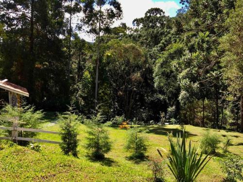 a garden with a fence and trees and grass at Casa Cipreste no Refúgio Pinheiro Beira Rio in Sapucaí-Mirim
