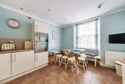 a kitchen with white cabinets and a table and chairs at Georgian Town House in Ilfracombe
