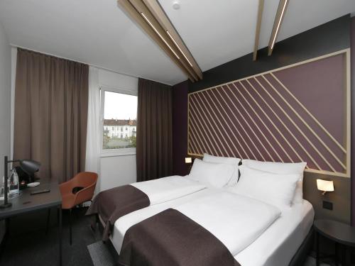 um quarto de hotel com uma cama, uma secretária e uma janela em B&B Hotel Berlin City-Ost em Berlim
