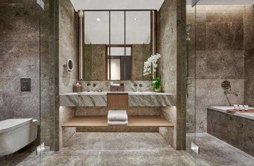 a bathroom with a tub and a sink and a mirror at Pan Pacific Jakarta in Jakarta