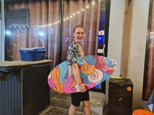 a man holding a surfboard in a room at The Rendezvous Fullmoon Hostel in Haad Rin