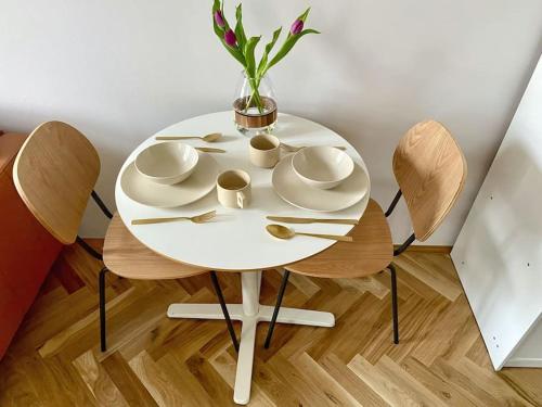 a white table with two chairs and a vase with flowers at Stylish Studio near Dejvická metro station in Prague