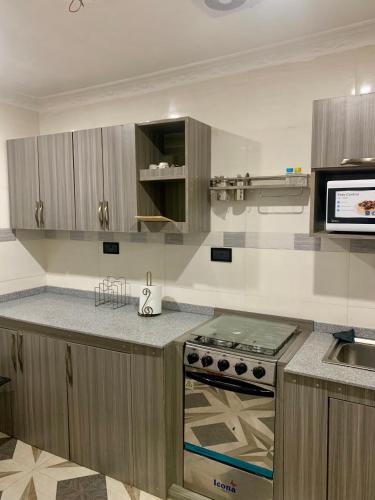 a kitchen with a stove and a microwave at M&C homes Akrowa in Accra