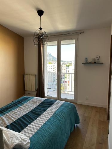 une chambre avec un lit et une grande fenêtre dans l'établissement Bel appartement, à Toulon