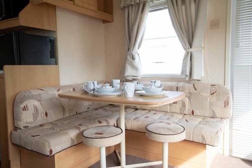 una mesa con tazas y platillos junto a un sofá en Skegness Caravans, en Skegness