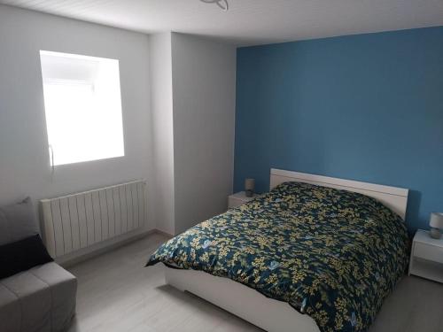 1 dormitorio con cama y pared azul en Gîte des deux petits doudous, en Colombey-les-deux-Églises