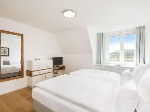 a white bedroom with a bed and a mirror at Kliffsand-72 in Kampen
