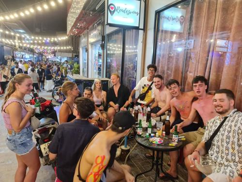 un grupo de personas sentadas alrededor de una mesa con botellas de cerveza en The Rendezvous Hostel, en Haad Rin