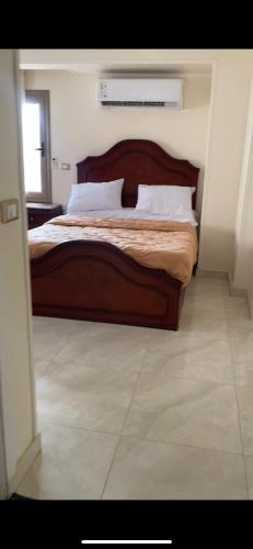 a bedroom with a bed with a wooden headboard at شقة فندقية مميزة بالمنصورة in Ṭalkha