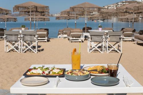 einen Tisch mit zwei Tellern Essen am Strand in der Unterkunft Agia Anna Beachfront Boutique in Strand Paraga