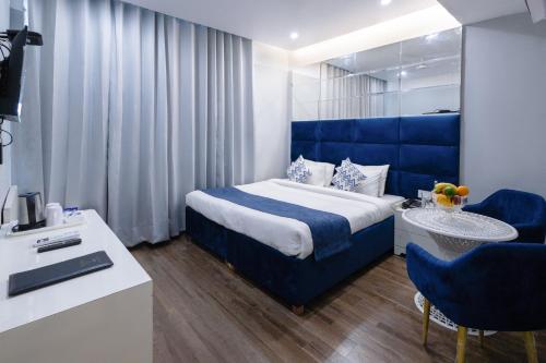 Habitación de hotel con cama azul y escritorio. en Hotel Downtown 17 en Chandigarh