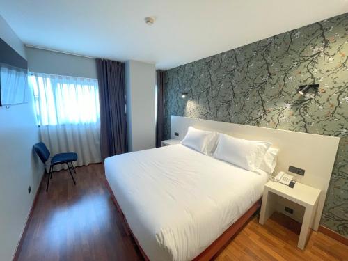 um quarto com uma grande cama branca e uma parede em Hotel San Fermín Pamplona em Burlada