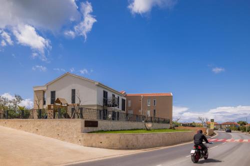 a man riding a motorcycle down a road at Salt and Stone Villa in Nin