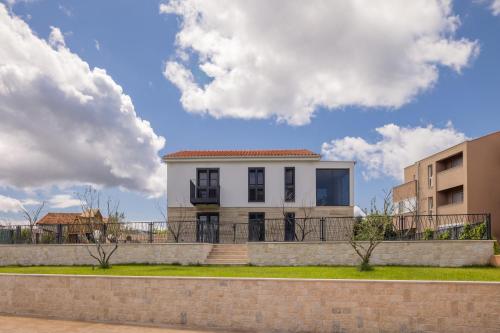 a white house with a fence in front of a building at Salt and Stone Villa in Nin