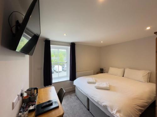 a bedroom with a bed and a desk and a television at The White Lion Hotel in Machynlleth