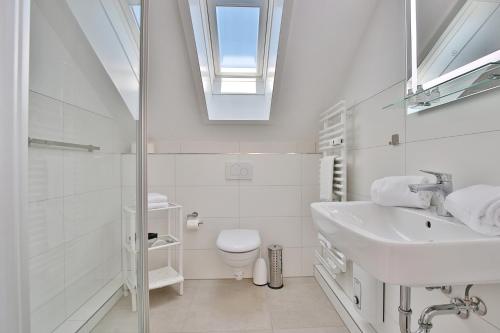 ein Badezimmer mit einem Waschbecken, einem WC und einem Dachfenster in der Unterkunft Haus Adria Haus Adria Appartement 29 in Scharbeutz