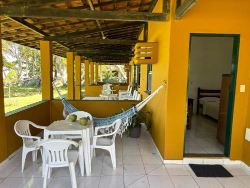 een veranda met een hangmat en een tafel en stoelen bij Pousada Casarão - Pé na Areia Cumuruxatiba in Cumuruxatiba