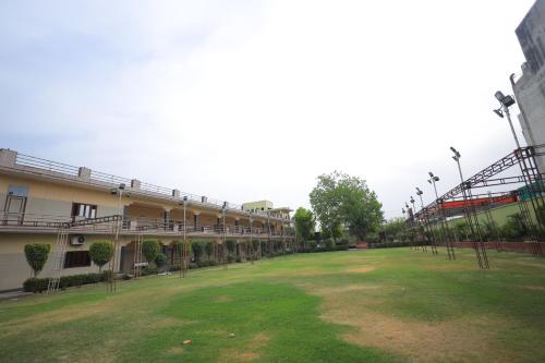 a building with a green field in front of it at Hotel Mukund Priya- Near Krishna Janam Bhoomi in Mathura