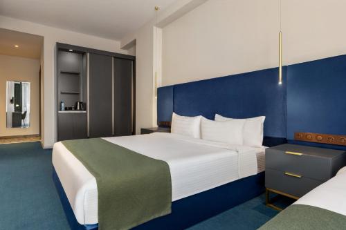 a hotel room with two beds and a blue wall at Ramada by Wyndham Tbilisi Old City in Tbilisi City
