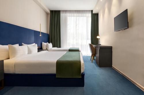 a hotel room with a large bed and a desk at Ramada by Wyndham Tbilisi Old City in Tbilisi City