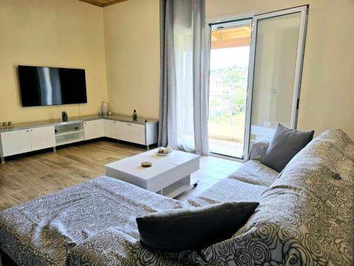 sala de estar con sofá y TV de pantalla plana en Philoxenia guest house, en Himare