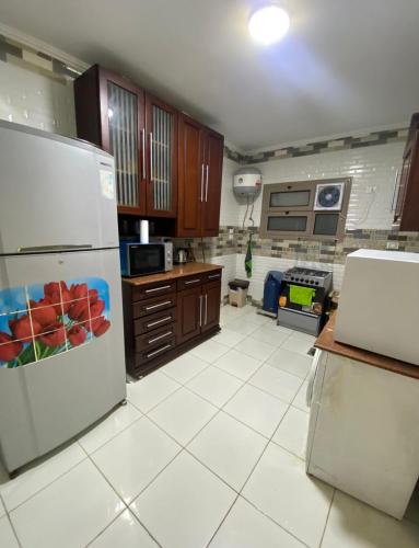 a kitchen with a white tile floor and a refrigerator at شقة فندقية مميزة بالمنصورة in Ṭalkha