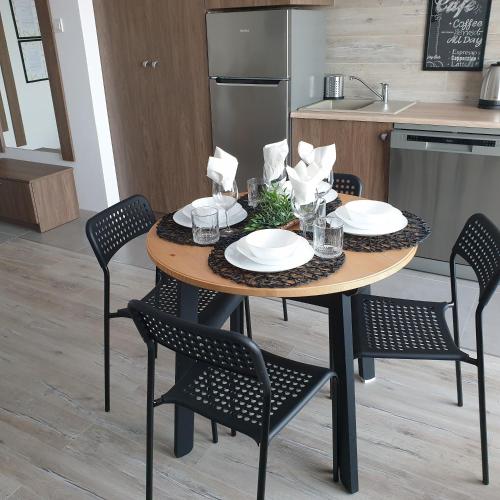 a table with four chairs and a kitchen at Q Apart Meta -1, 2 lub 3-pokojowe, klimatyzowane apartamenty przy Manufakturze z garażem lub parkingiem Gratis, FV in Łódź