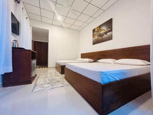 - une chambre avec un grand lit et une télévision dans l'établissement Meegahasewana Bungalow, à Kurunegala