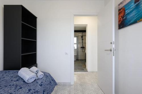 a bedroom with white walls and a bed with towels at Modern Comfort App in Las Palmas GC in Las Palmas de Gran Canaria