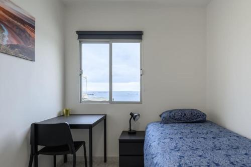 a bedroom with a bed and a desk and a window at Modern Comfort App in Las Palmas GC in Las Palmas de Gran Canaria