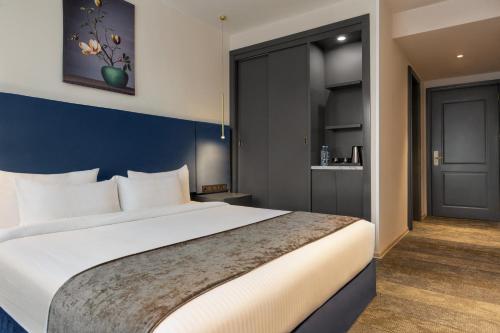 a bedroom with a large white bed and a blue wall at Ramada by Wyndham Tbilisi Old City in Tbilisi City