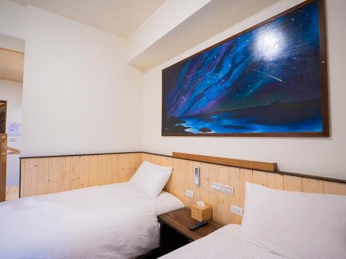 two beds in a room with a tv on the wall at Chin-Be in Beigan