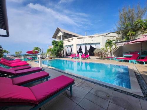 - une piscine avec des chaises longues roses à côté d'un bâtiment dans l'établissement Mui Ne Hills Backpackers, à Mui Ne