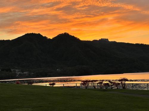 a sunset over a body of water with a mountain at Toyako Guest House Ponkotan in Lake Toya